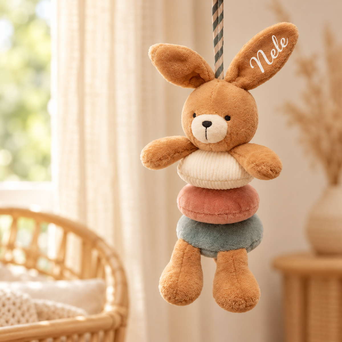 Personalisierte Hasen-Spieluhr mit Namen „Nele“ im Ohr, hängend vor hellen Leinenvorhängen im Boho-Kinderzimmer
