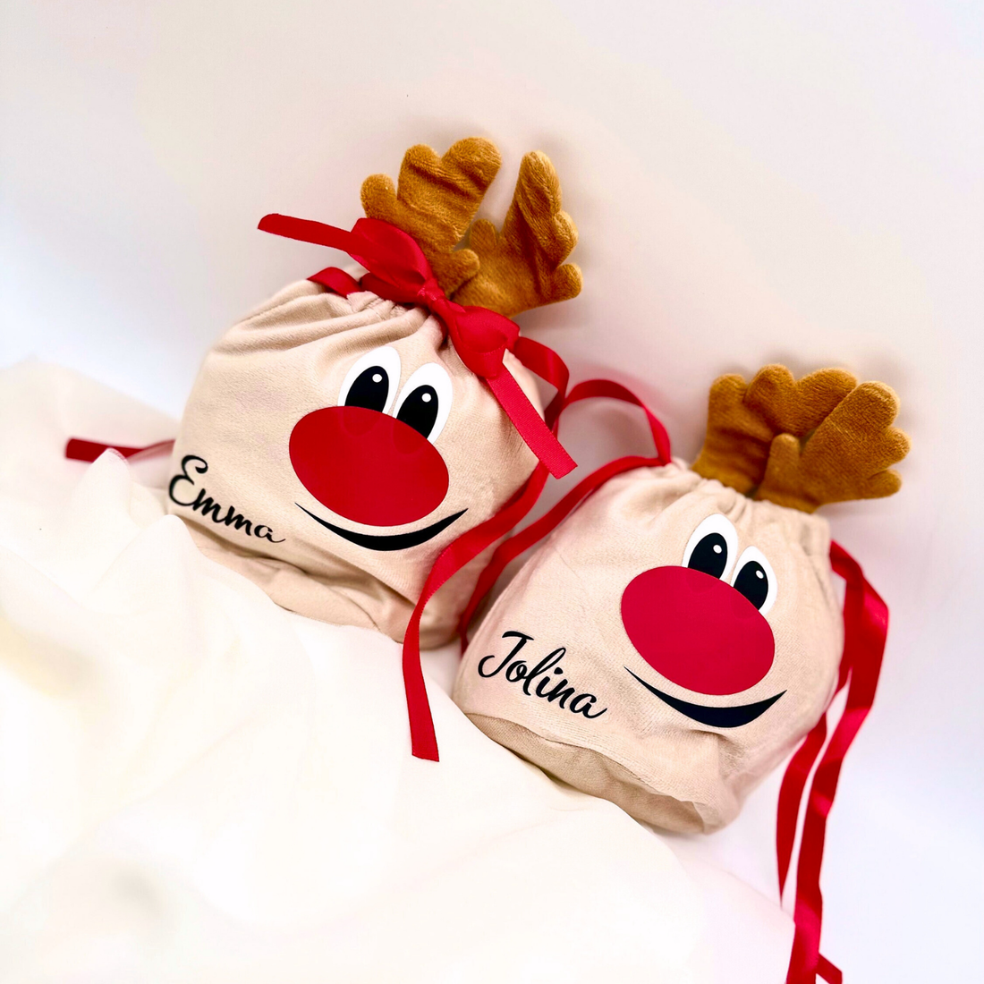 Zwei personalisierte Rentier-Geschenksäckchen mit roten Bändern und den Namen Emma und Jolina