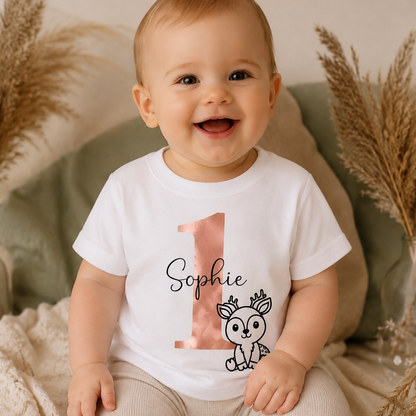 Fröhliches Baby trägt ein personalisiertes T-Shirt zum 1. Geburtstag mit roségoldener Zahl 1, Wunschname Sophie und niedlichem Rehmotiv. Individuelles Geschenk zum ersten Geburtstag für Mädchen.
