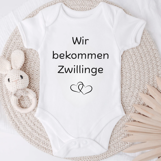 Süßer Baby Body zur Schwangerschafts verkündung von Zwillingen. Wir bekommen Zwillinge ist der Spruch mit 2 Herzen