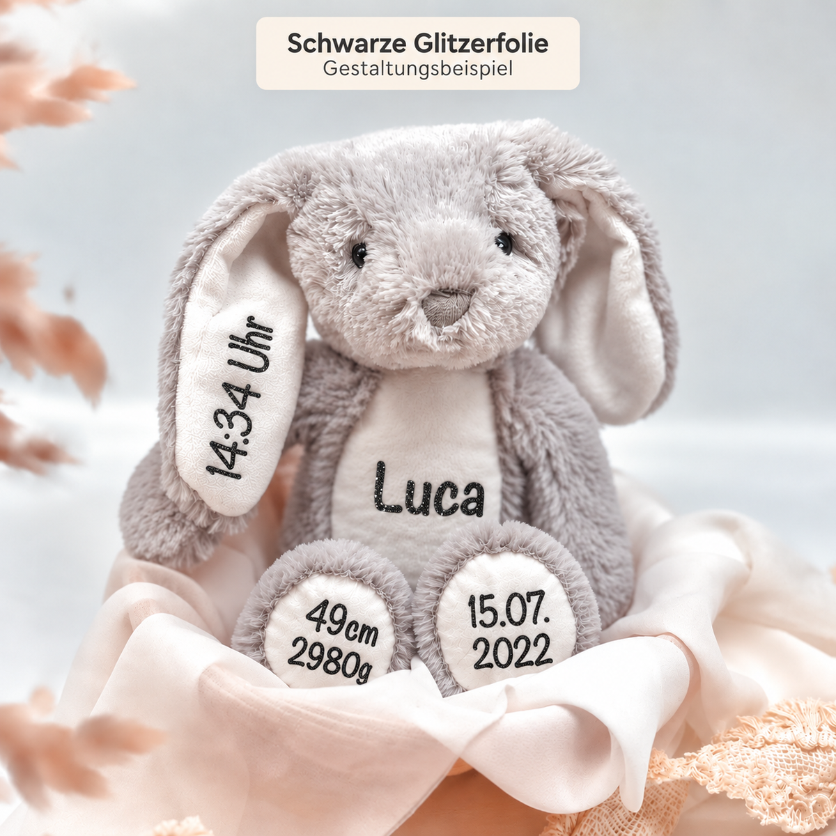 Gestaltungsbeispiel des grauen Kuschelhasen Luca mit Name und Geburtsdaten in schwarzer Glitzerfolie